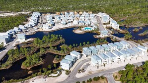 An aerial view of a residential area with multiple houses, a swimming pool, and a road.