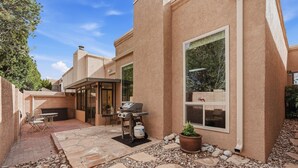Un patio con una parrilla, mobiliario exterior y un sendero de piedra.