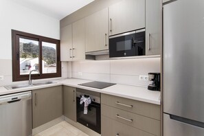 Eine moderne Küche mit Edelstahlgeräten, einem Geschirrspüler und einem Fenster mit Blick auf die Berge.