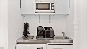 A compact kitchenette with a microwave, coffee maker, and a sink. - Studio Raffine Quartier La Muette (Paris)
