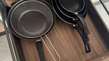 Een houten lade met twee keukenaccessoires: een vergiet en een anti-aanbakpan.