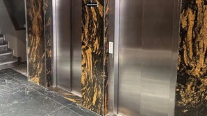 A modern elevator with a marble finish and a wooden panel above it. - Studio in city center (Fès)