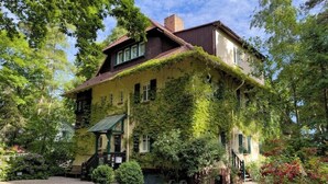 A historic building with ivy-covered walls, a traditional gabled roof, and a front porch. - Strandvilla Hubertus - H2 - Frida Kahlo (Ostseebad Boltenhagen)