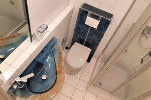 Kylpyhuoneessa on sininen pesuallas, wc ja suihku.