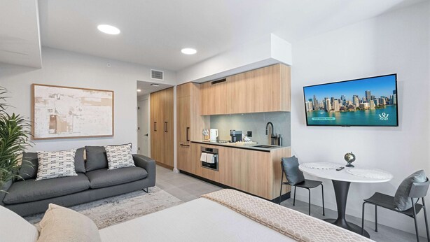 Un apartamento moderno con kitchenette, zona de comedor y sala de estar con sofá y cama.