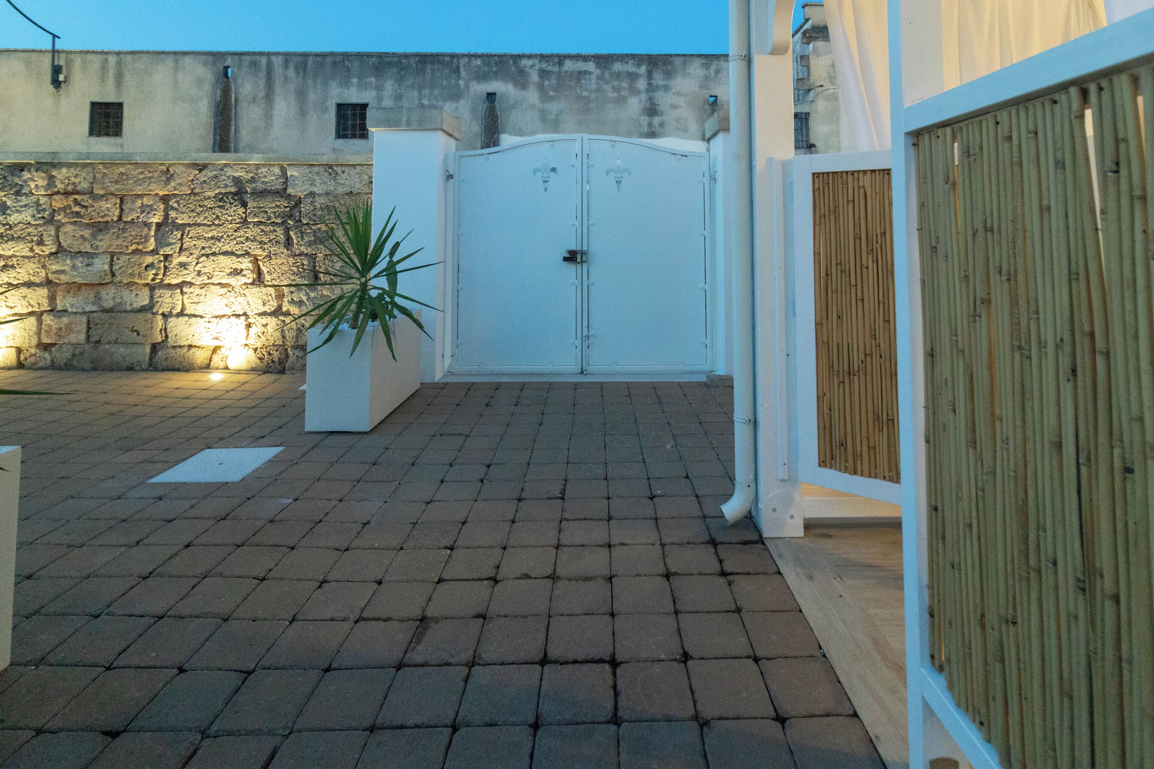 Un patio con suelo empedrado, una puerta blanca y un muro de piedra.