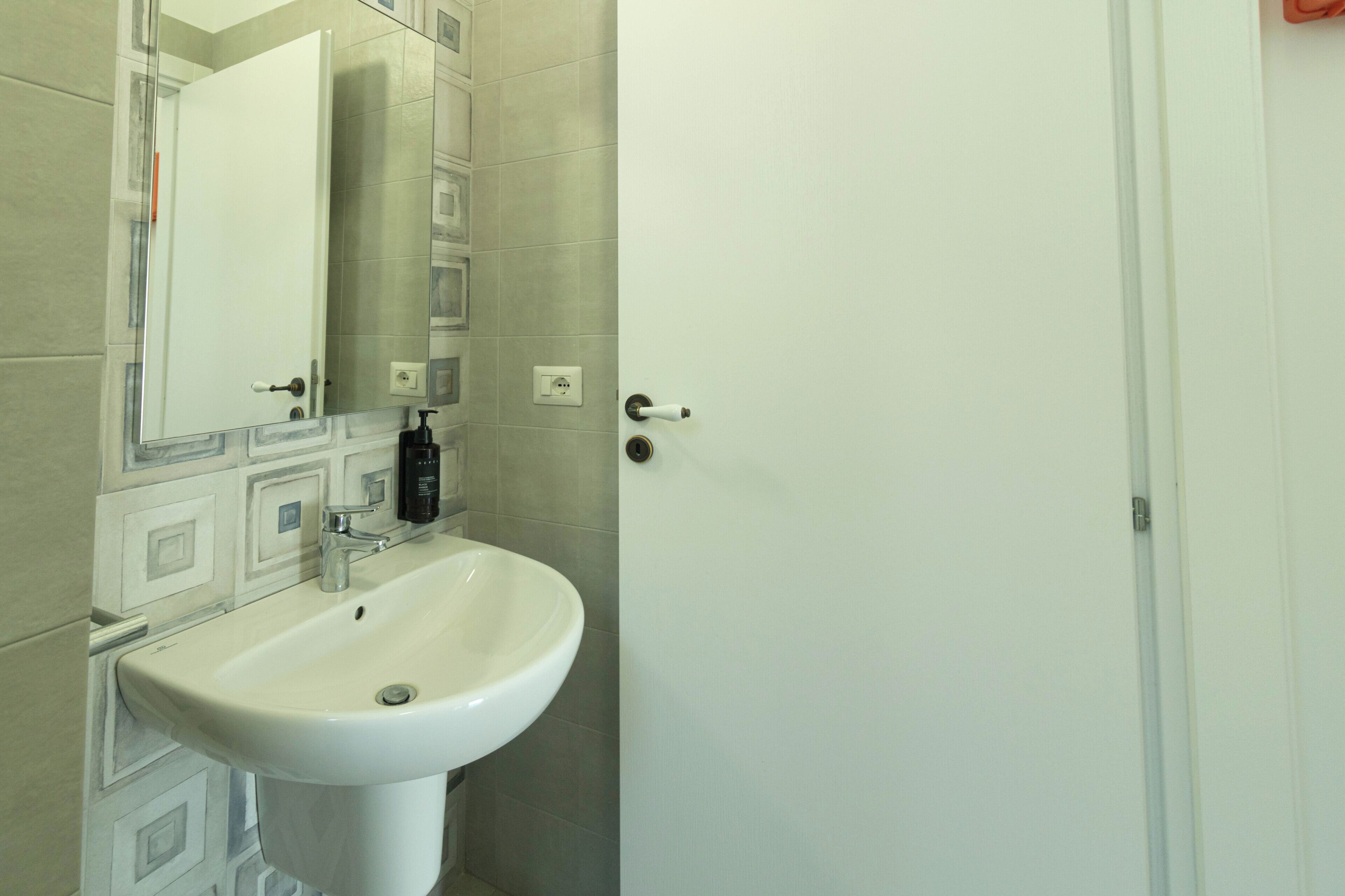 A bathroom with a white sink, a mirror, and a door.