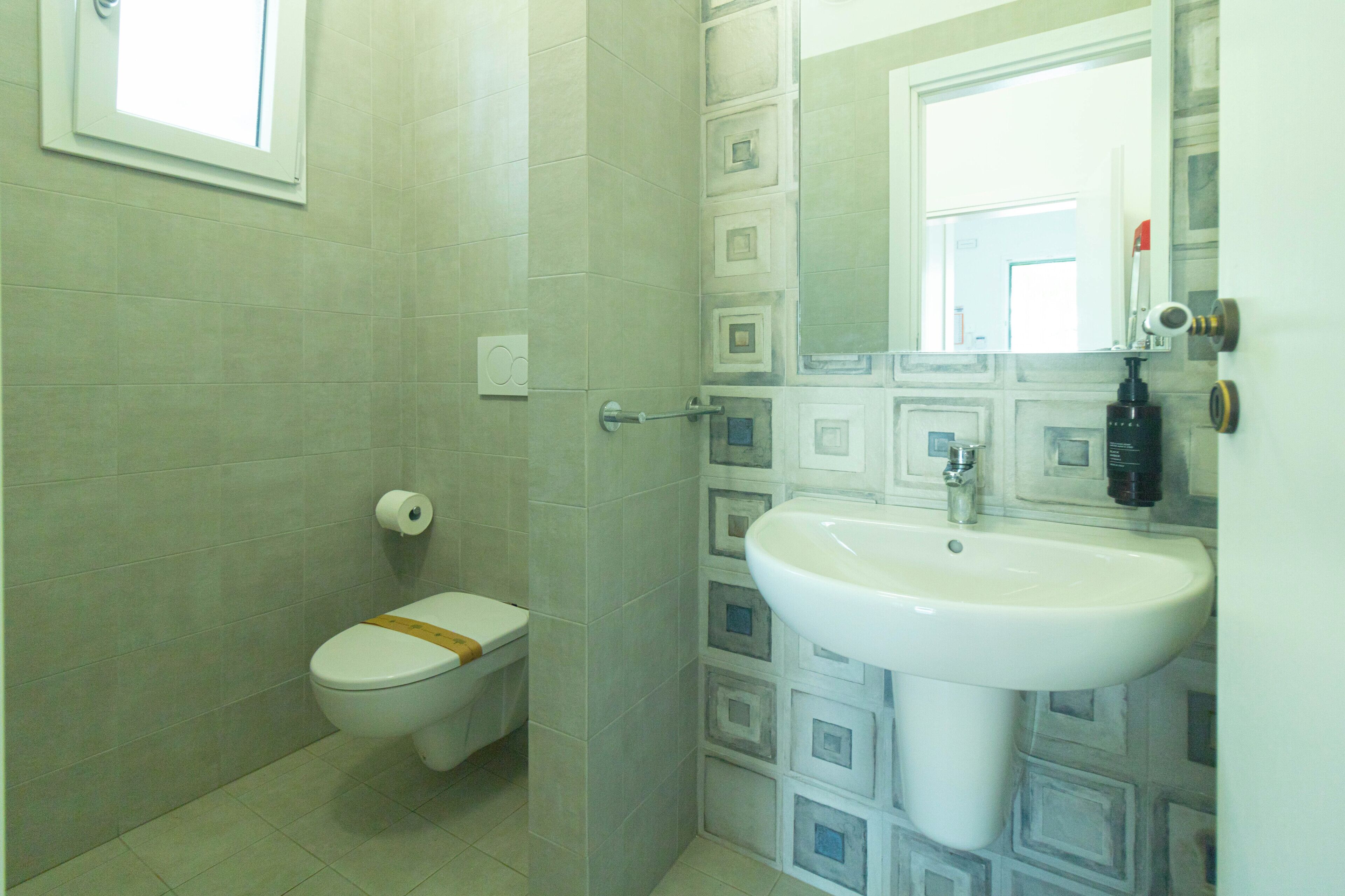 A bathroom with a toilet, sink, and mirror.