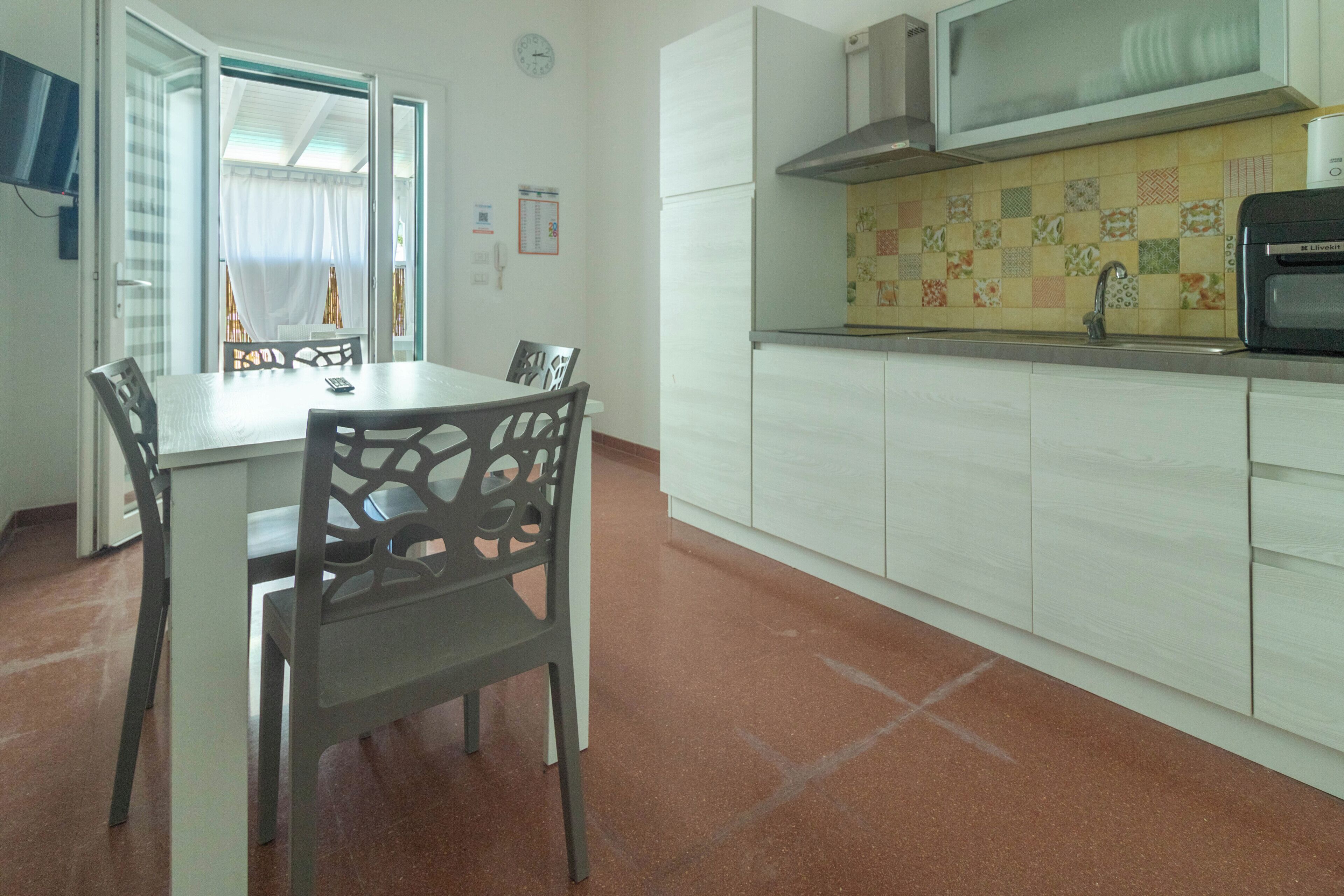A compact kitchen with a microwave, sink, and tiled backsplash.