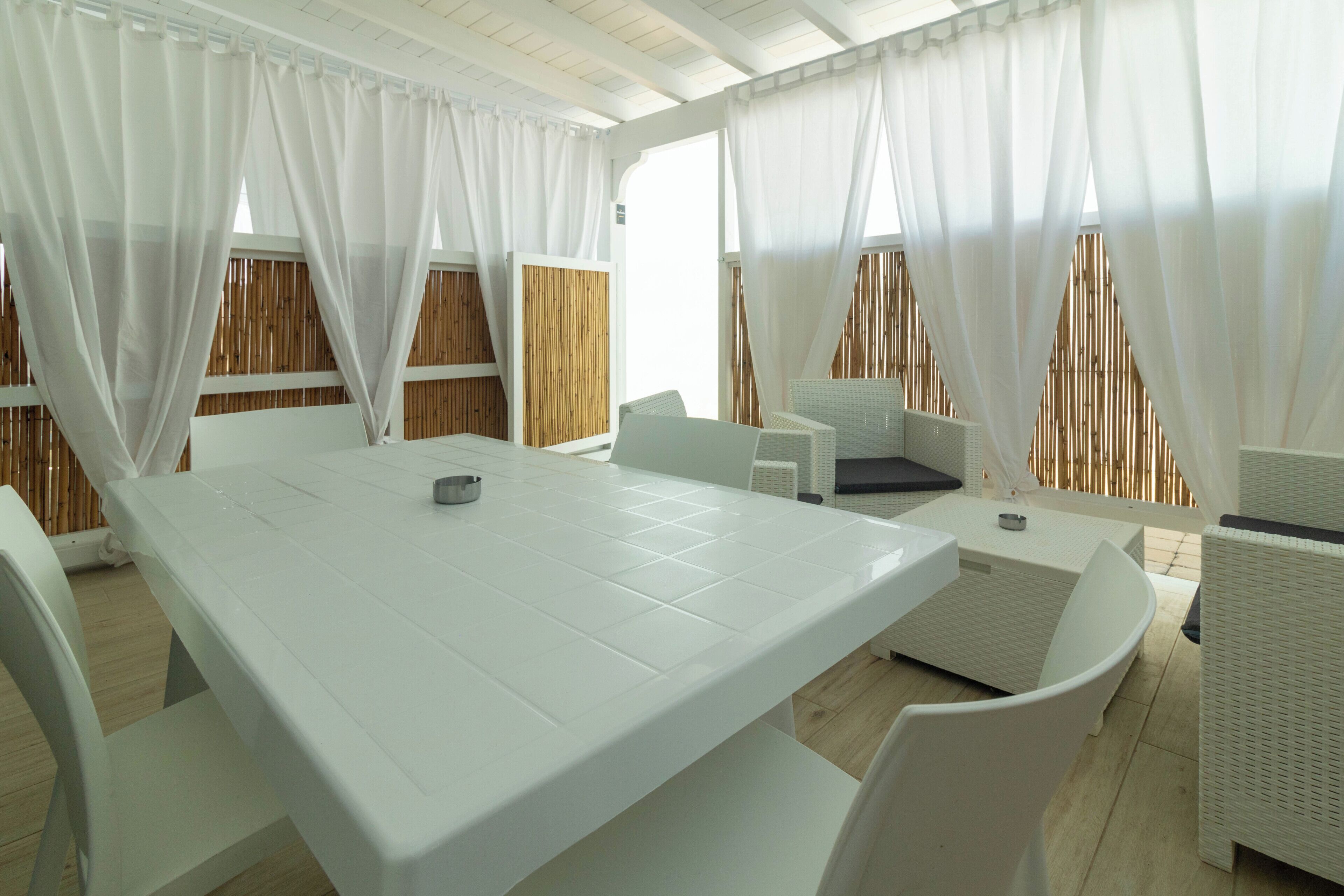 A spacious room with a large white table, white chairs, and a sofa.