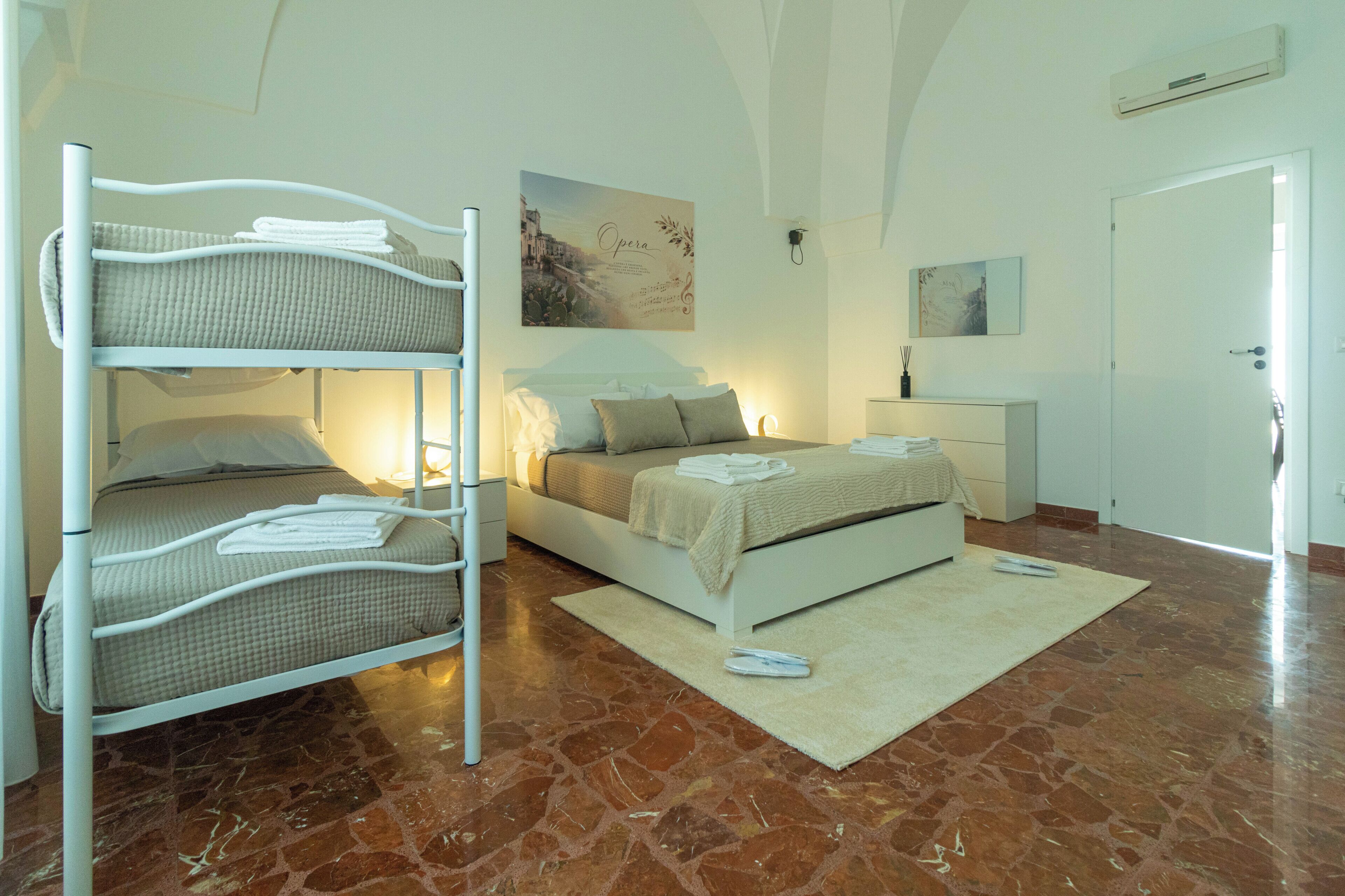 A bunk bed room with a single bed, a nightstand, and a painting on the wall.