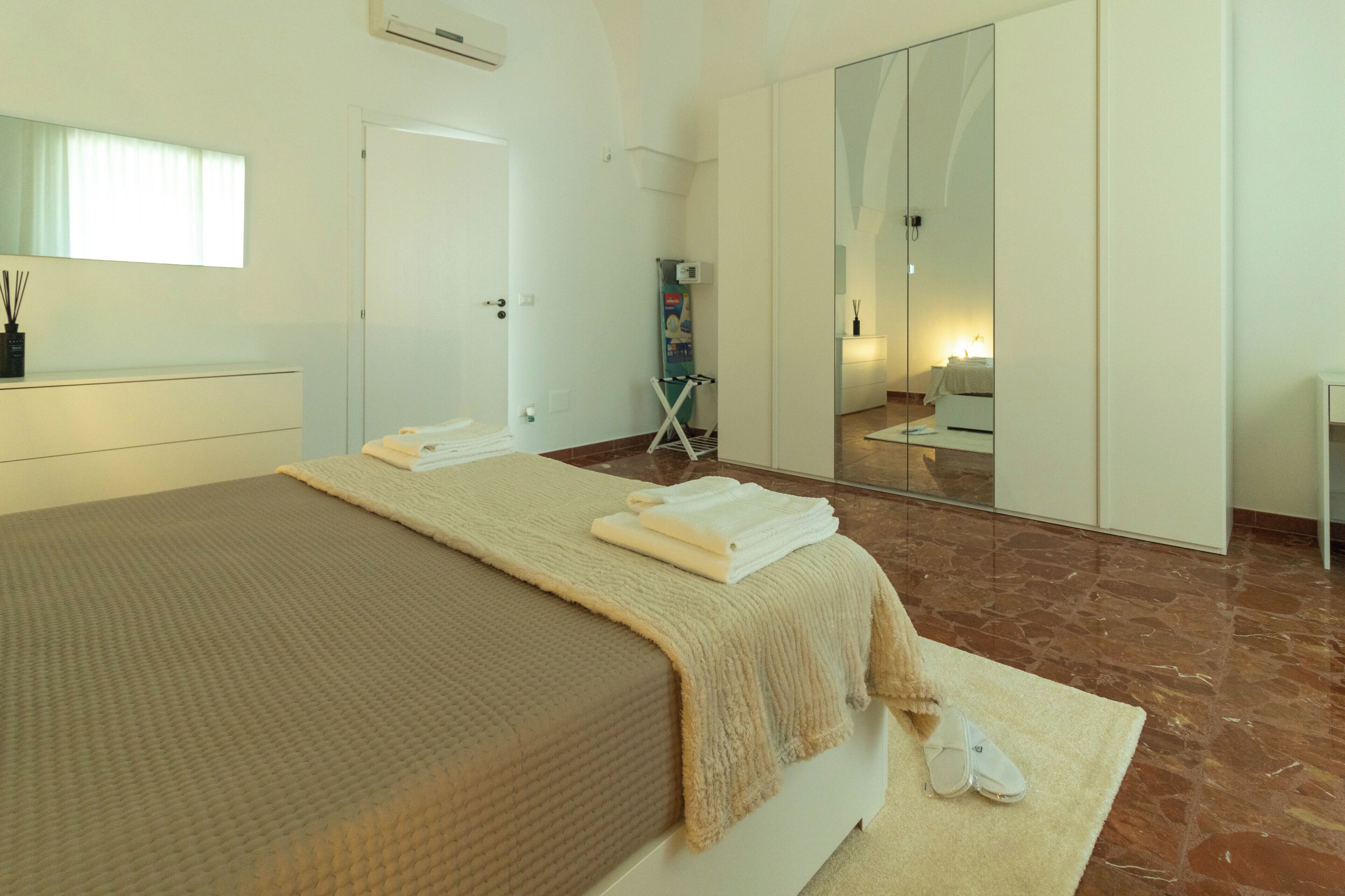 A hotel room with a bed, a mirror, a wardrobe, and a bathroom.