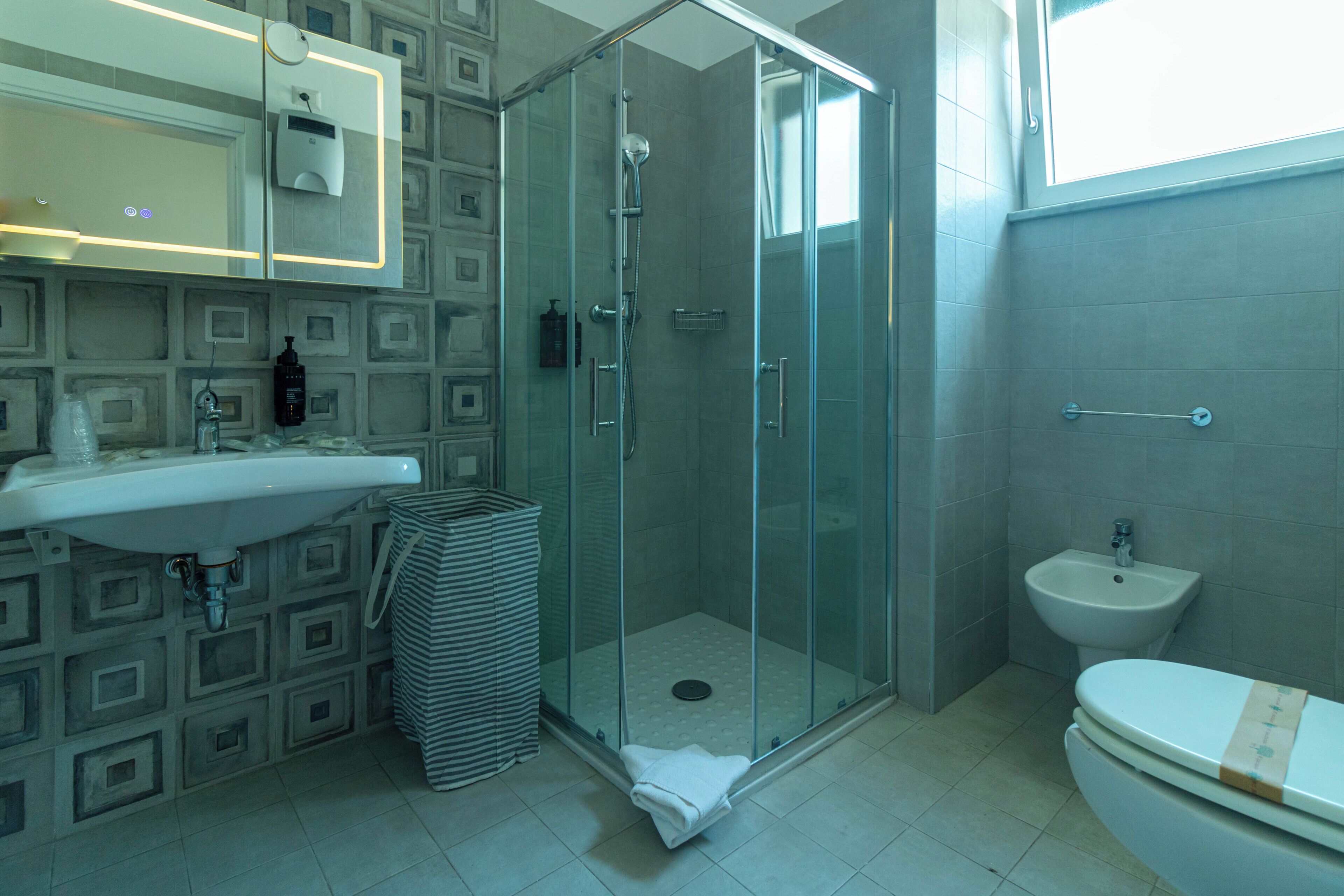 Un baño con ducha de vidrio, lavamanos, bidé y retrete.