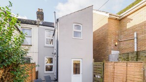 A residential building with a grey exterior, a white door, and a small window. - Host & Stay | Roach Street (Rochester)
