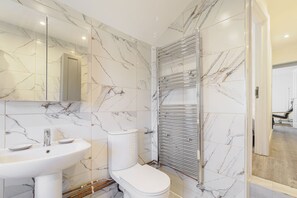 Une salle de bain avec un lavabo blanc, des toilettes et une cabine de douche en verre.