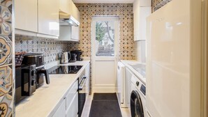 A compact kitchen with a microwave, stove, and washing machine. - Host & Stay | Roach Street (Rochester)
