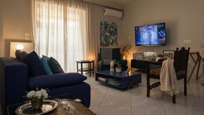 Un salon avec un canapé, une table basse, un téléviseur et un fauteuil.