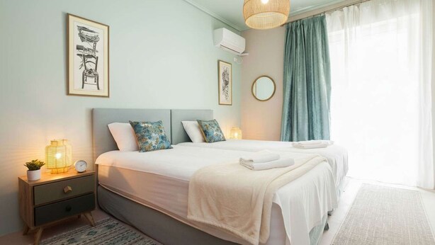Une chambre à coucher bien rangée, avec un lit, des tables de chevet et des œuvres d’art accrochées au mur.
