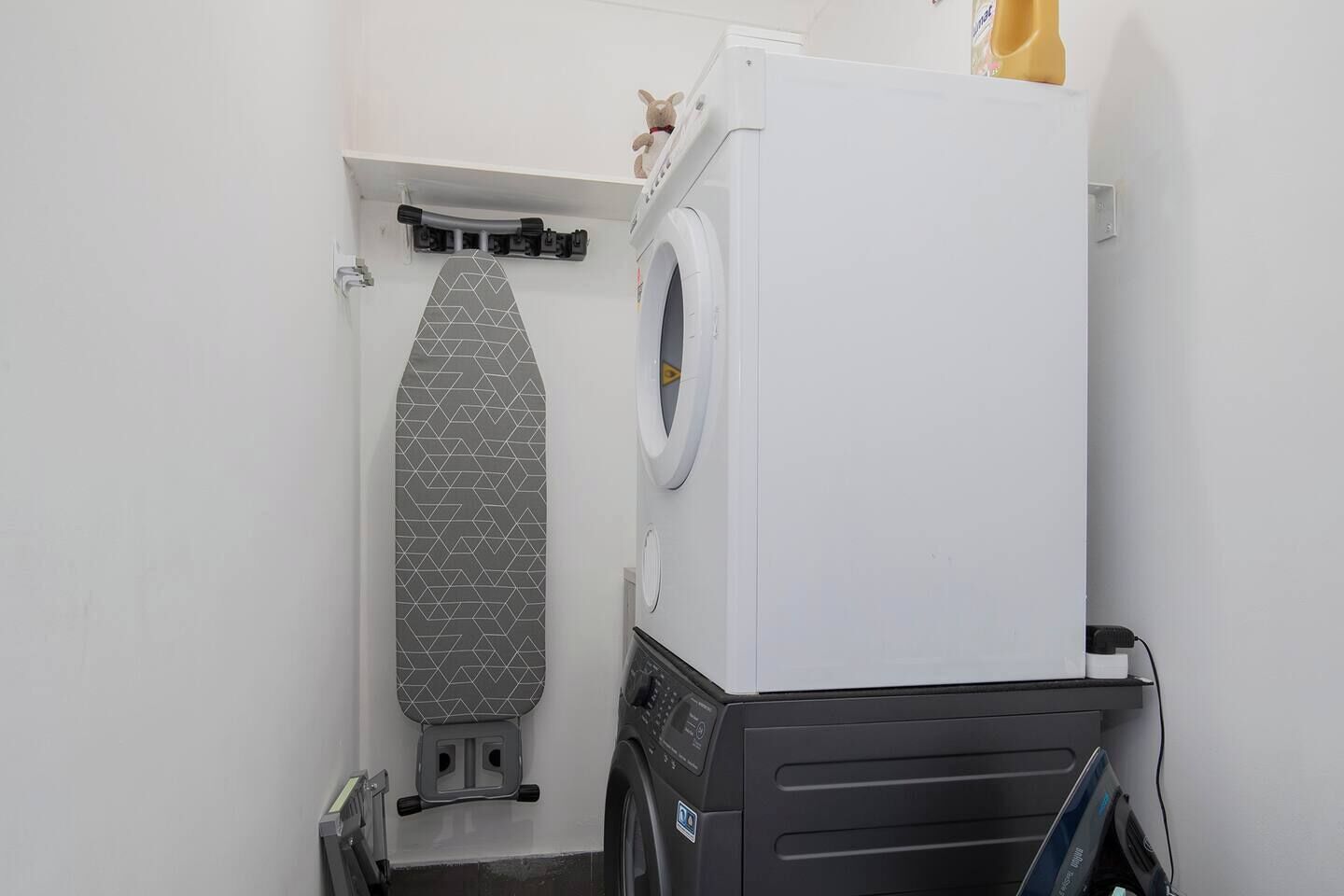 A compact laundry room with a washing machine, a dryer, and a wall-mounted ironing board.