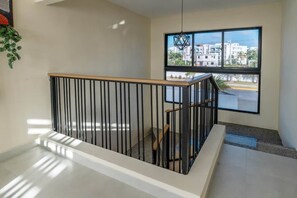 A modern interior with a staircase, a large window offering a view of buildings, and a hanging light fixture. - Atabey Luxury Paradise (Punta Cana)