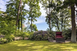 A garden with a bench, a small red structure, and lush greenery. - Strandvilla Hubertus - H3 - Gustav Klimt (Ostseebad Boltenhagen)