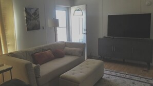 A living room with a sofa, ottoman, TV, and a cabinet. - Eagle's Nest- A Tranquil 3-bedroom home with amazing views in charming Espanola (Espanola)