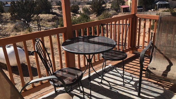 A wooden deck with a table and chairs, overlooking a mountainous landscape. - Eagle's Nest- A Tranquil 3-bedroom home with amazing views in charming Espanola (Espanola)