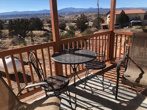 A wooden deck with a table and chairs, overlooking a mountainous landscape. - Eagle's Nest- A Tranquil 3-bedroom home with amazing views in charming Espanola (Espanola)
