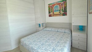Un dormitorio con cama, armario, estante y un cuadro en la pared.