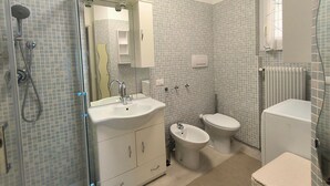 Un baño con ducha, lavamanos, bidé, inodoro y un radiador.