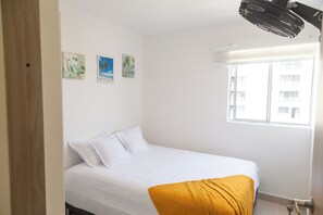 Ein Schlafzimmer mit einem Bett, einem Fenster und drei Wandbildern.