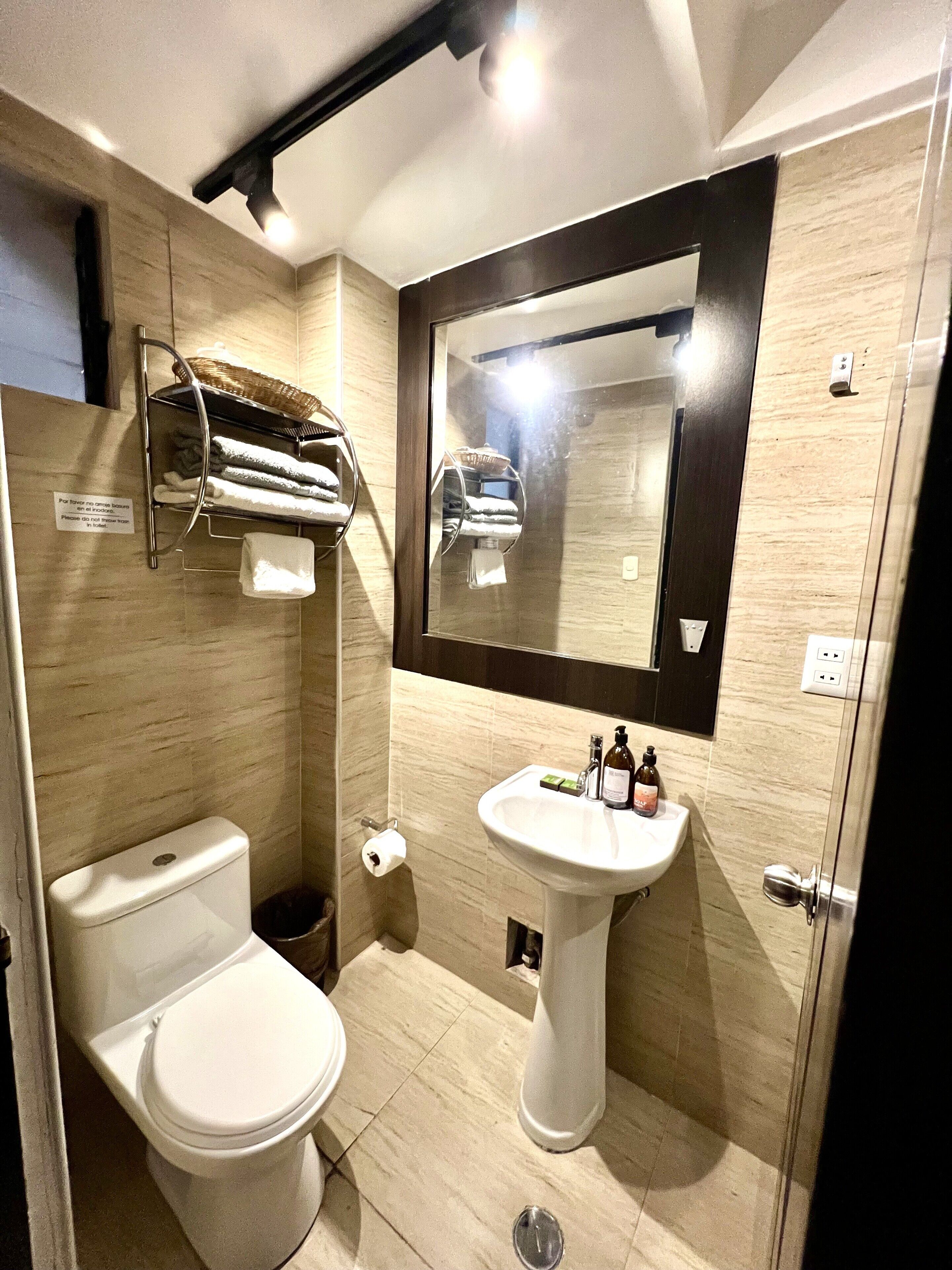 Ein Badezimmer mit Toilette, Waschbecken, Handtuchhalter und Spiegel.