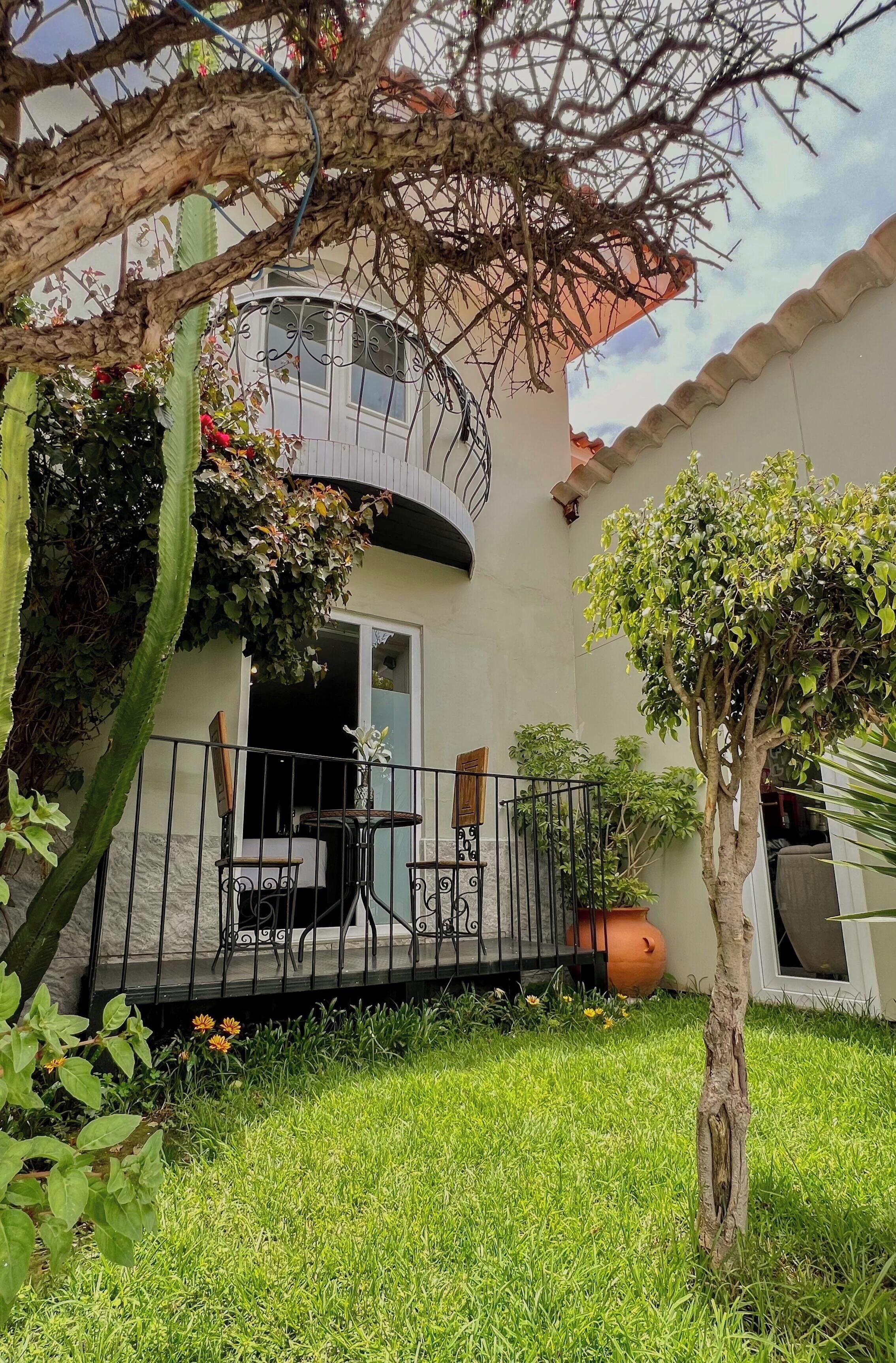 Une maison avec un balcon, un petit jardin et un cactus.