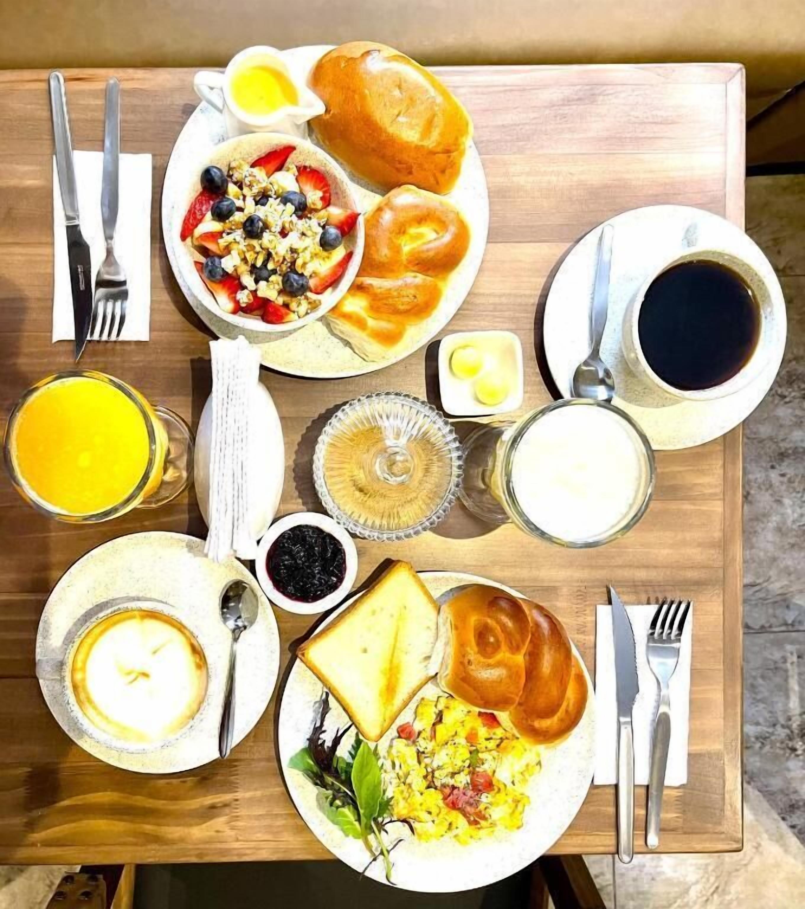 A breakfast table with various dishes including toast, eggs, and a fruit salad.