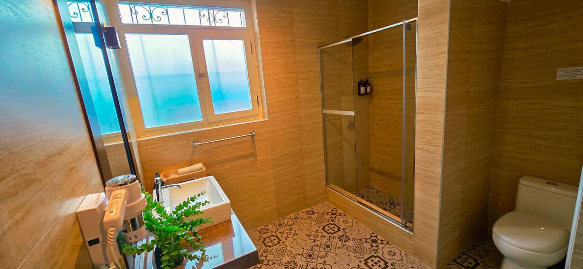Bagno con doccia, lavandino, water e una finestra vista.