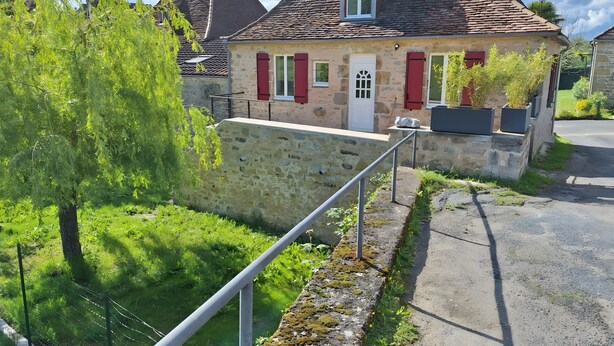 Un bâtiment en pierre avec des volets rouges, une porte blanche et une petite fenêtre.