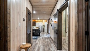 A wooden interior hallway with a sofa and a table, leading to a kitchen area. - Broken Bow Cabin with Hot Tub and Game Room (Broken Bow)