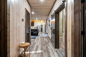 Pasillo interior de madera con sofá y una mesa, que conduce a una zona de cocina.