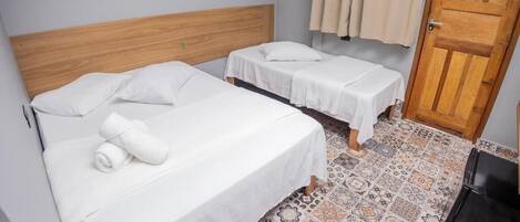 A room with two beds, a wooden headboard, a patterned floor, and a door.