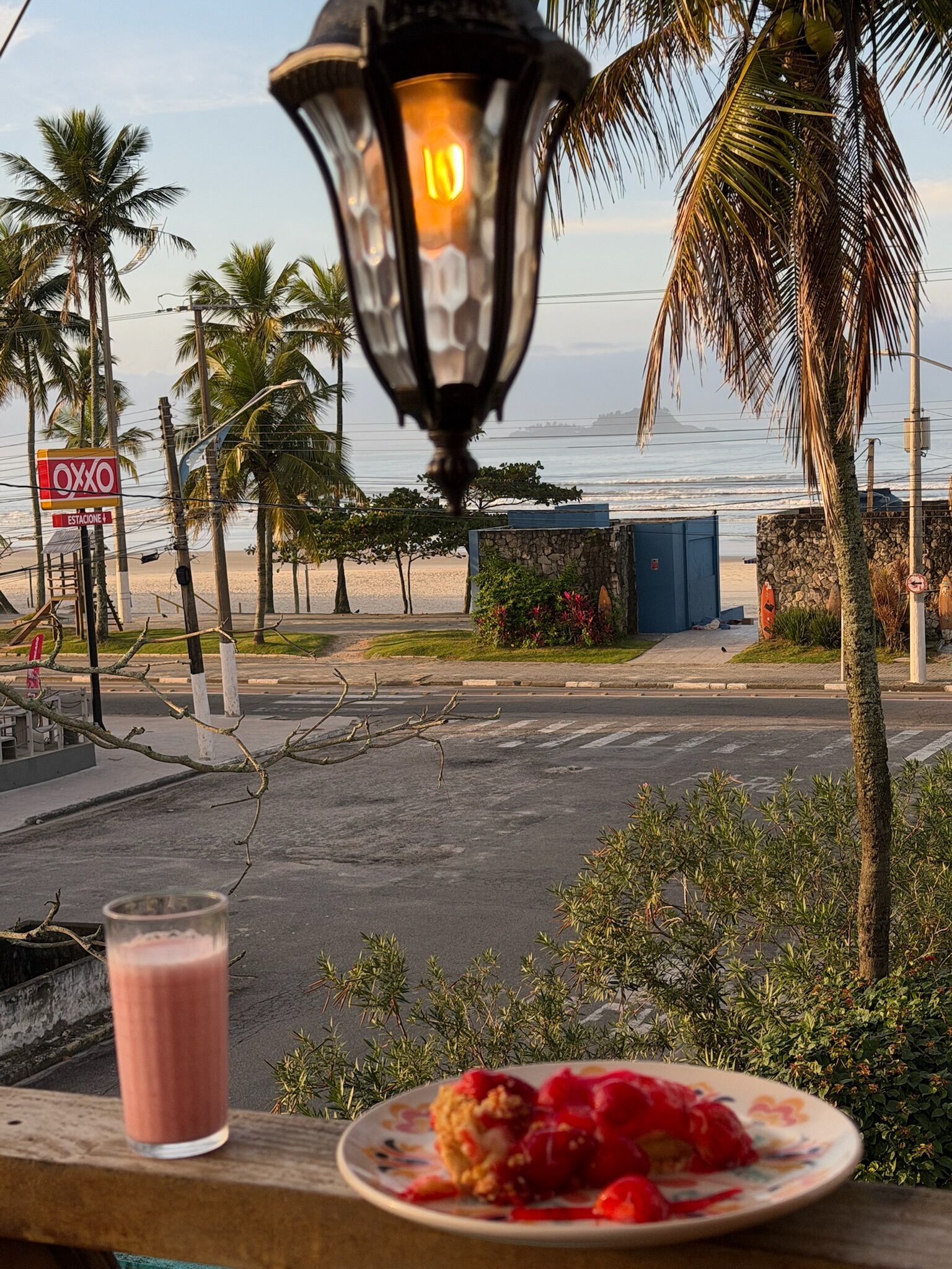Une vue sur la plage avec un lampadaire, des palmiers et une enseigne indiquant « Oxxo ».