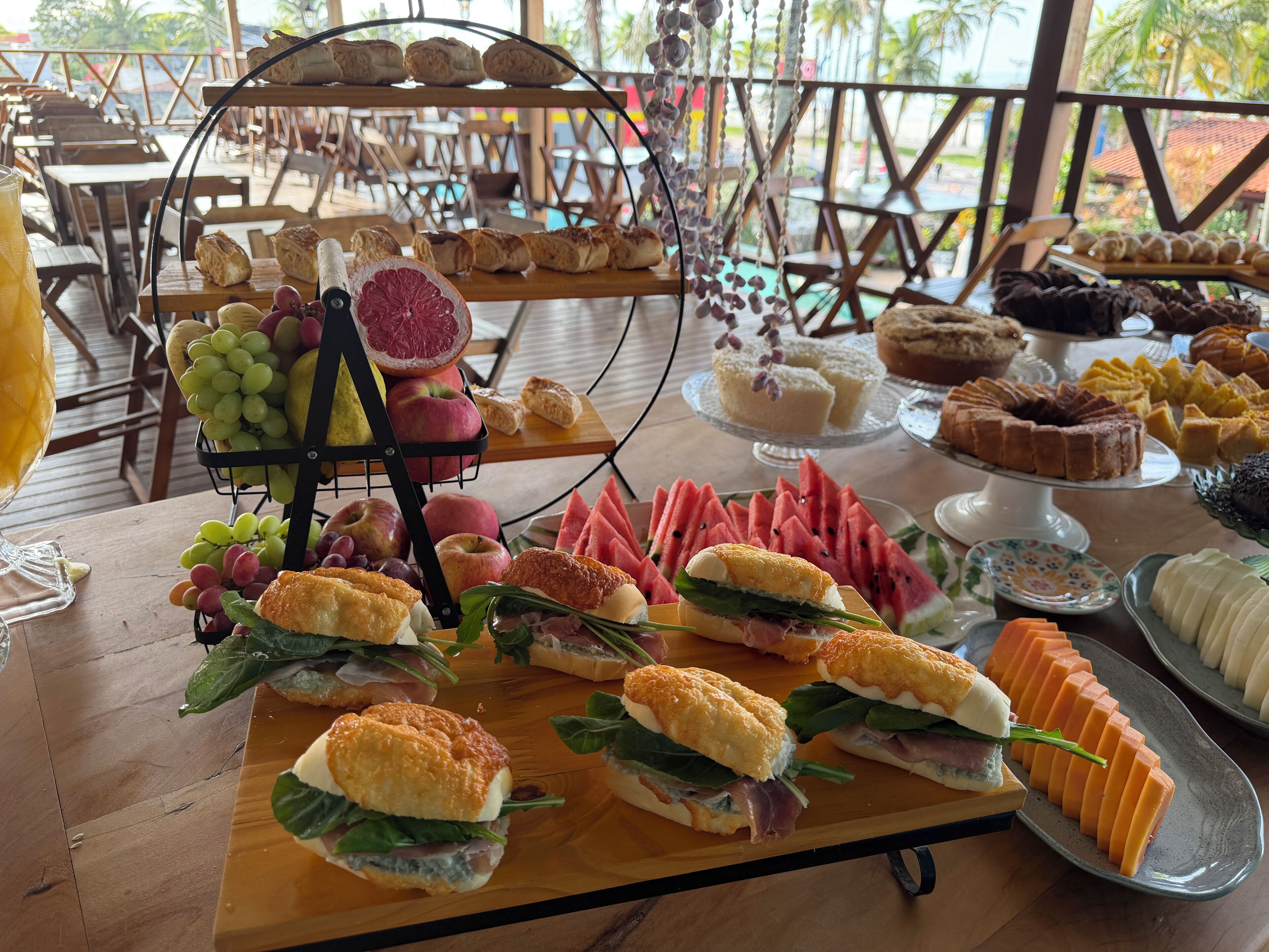 A buffet table with various food items including sandwiches, fruits, and pastries.