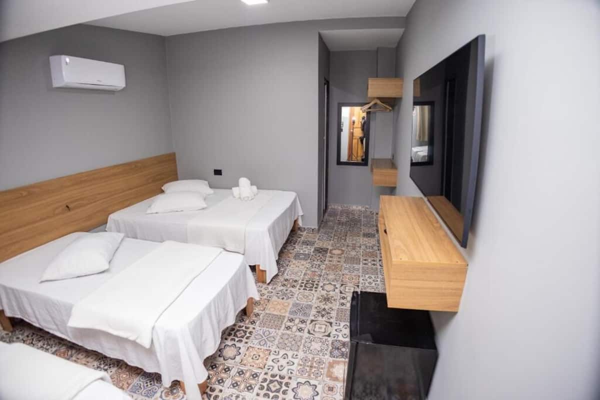 Ein Hotelzimmer mit zwei Einzelbetten, einem Holzkopfteil, einem großen Spiegel und einem Fliesenboden.