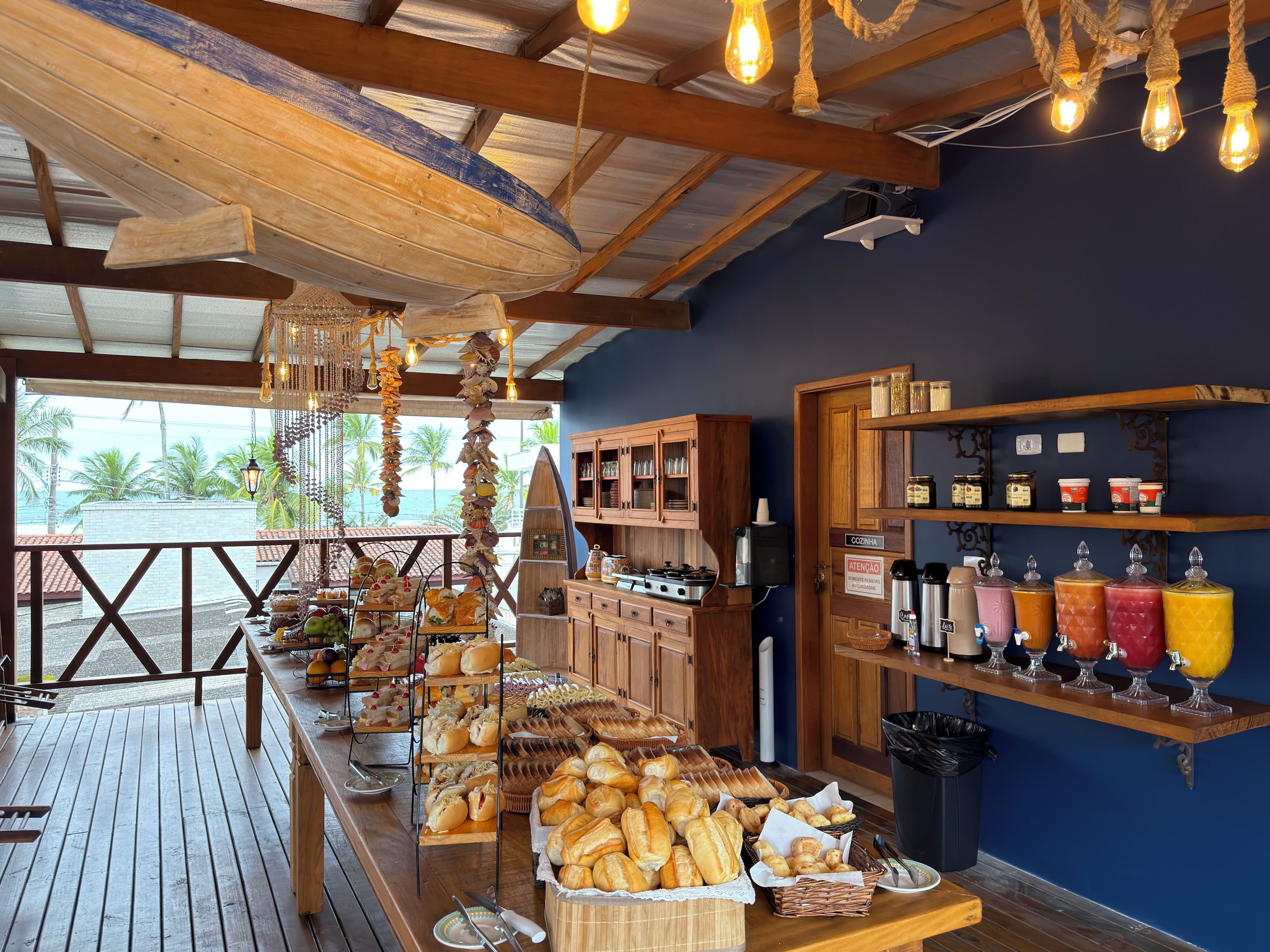 Een buffetgedeelte met diverse gerechten, een keuken met houten kasten, en uitzicht op de oceaan.