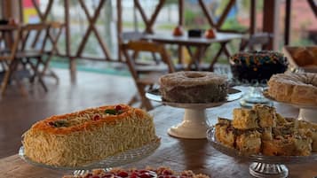 Diversos postres sobre una mesa en un comedor con vista a palmeras.