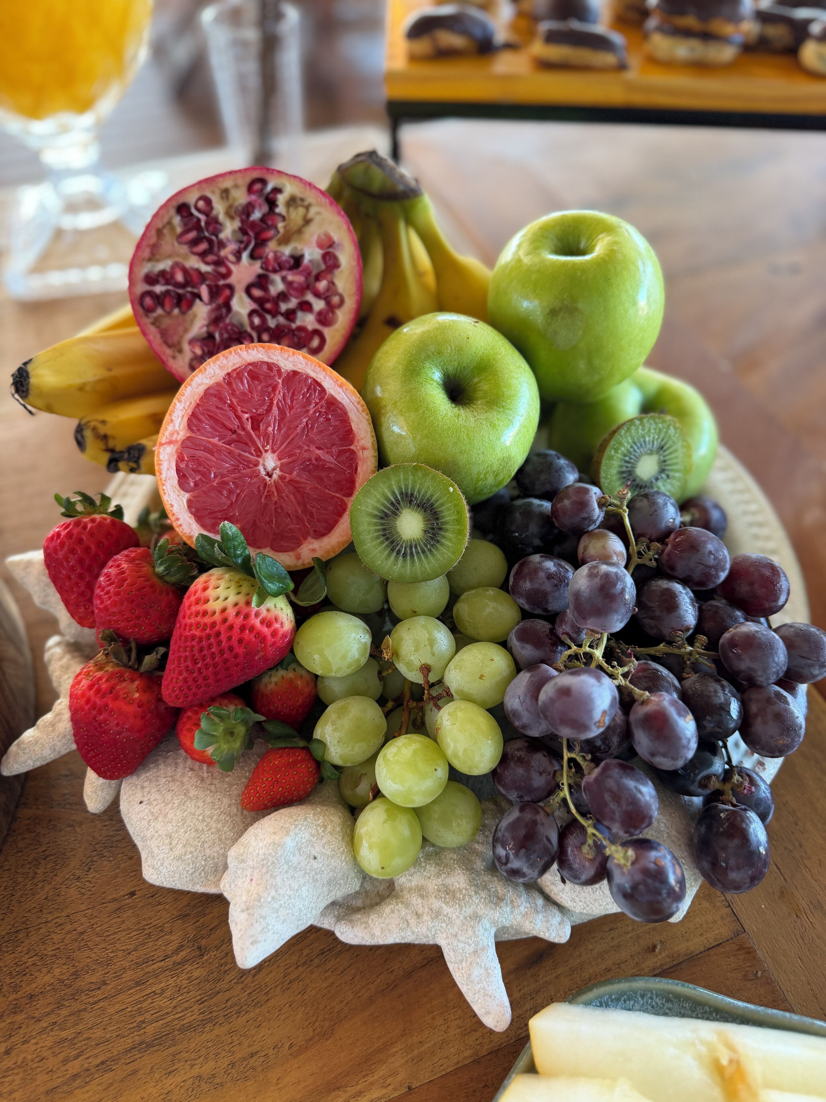 A fruit platter with strawberries, grapes, kiwi, pomegranate, and bananas.