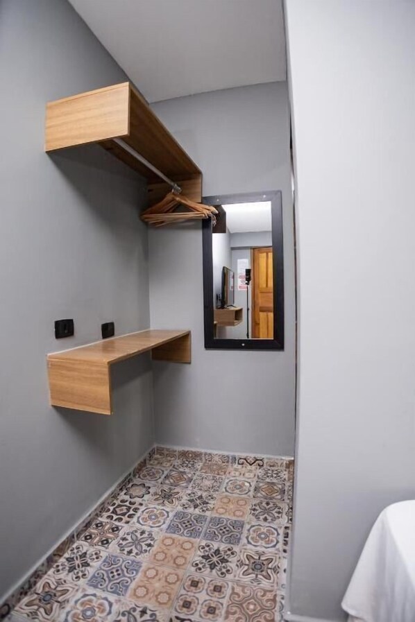 A narrow hallway with a tiled floor, a wooden shelf, and a mirror on the wall. - Santa Clara Pousada (Guarujá)
