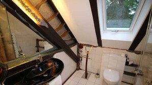 Un baño con lavamanos negro, inodoro blanco y una ventana.