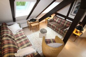 A loft-style room with a high ceiling, exposed beams, a sofa set, a small table, and a lamp. - Strandvilla Hubertus - H5 - Tamara de Lempicka (Ostseebad Boltenhagen)