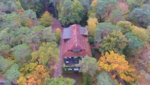 An aerial view of a house surrounded by dense forest with a red roof. - Strandvilla Hubertus - H6 - Paul Signac (Ostseebad Boltenhagen)