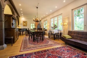 A spacious dining area with a chandelier, wooden furniture, and large windows. - Beach Villa Hubertus - H8 - Henri Toulouse Lautrec (Ostseebad Boltenhagen)